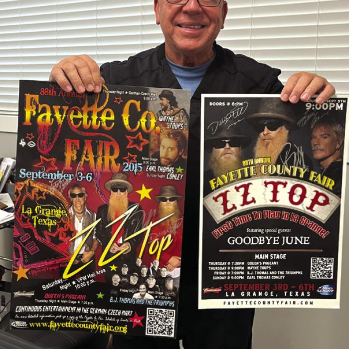 Dr. Larry Hatfield, the Fair President in 2015 who orchestrated the ZZ Top concert here, holds up, last week, a pair treasured items he kept from the show – concert posters he got the band to autograph 10 years ago. Photo by Jeff Wick