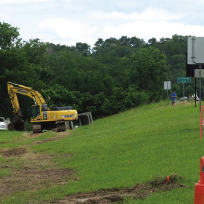Folks in La Grange have probably noticed the large excavator near the Colorado River Bridge on U.S. 77. City Manager Jack Thompson said the machine is being used to install some large box culverts that are part of the City stormwater drainage improvement project. Photo by Andy Behlen