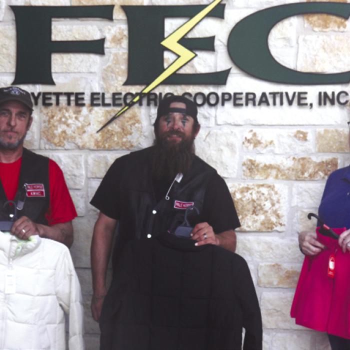 Palehorse Motorcycle Club President John Sturrock, Vice President James Risinger, and FEC Director of Marketing, Training, and Communication Tracy Denton display coats donated to FEC’s Coat Connection coat drive, highlighting the strength of community collaboration.