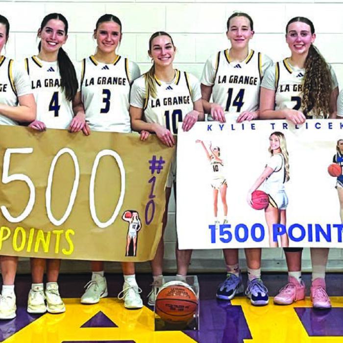 The members of the La Grange girls basketball team pose with Kylie Trlicek, center, after Tuesday’s game to honor her reaching the 1,500 career point milestone. Below, Trlicek, poses with one of her banners.