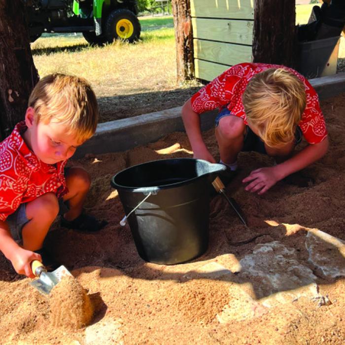 Two young visitors practice their mock excavation skills by searching for artifacts in the site’s special dig pit.