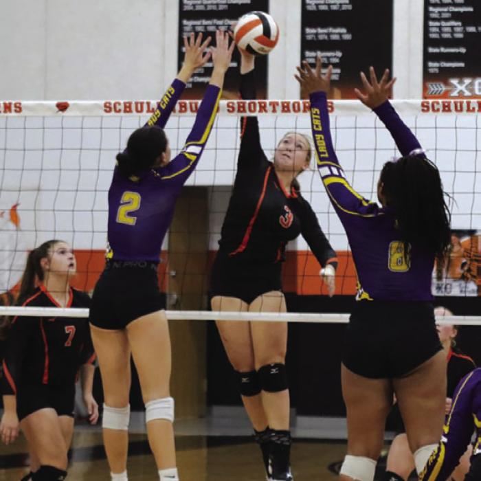 Schulenburg’s Reagan Dusek spikes a ball between two Weimar defenders Tuesday. Photo by Audrey Kristynik