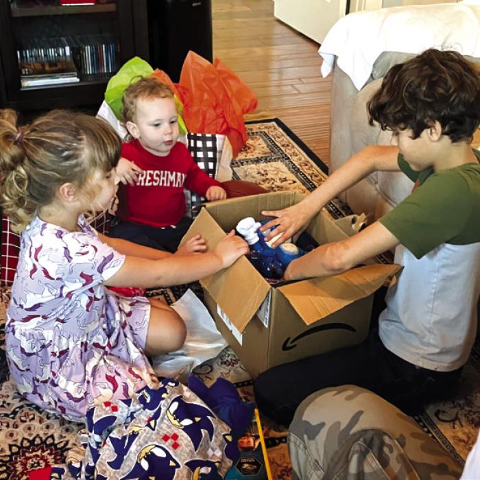 Nancie and Billie Blair’s great grandkids, Cason Blaha, Candence Schick and Luke Simpson, opening their gifts.