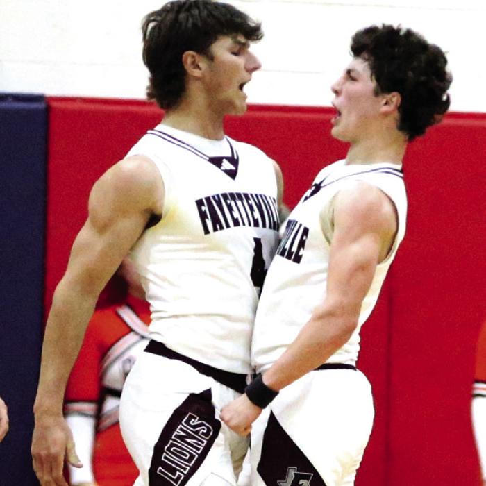 Lion seniors Jack Schley (left) and Mason Fenhaus do a chest bump to celebrate Schley’s huge block of a Wells shot attempt to send the game into overtime. Photo by Ken Sury