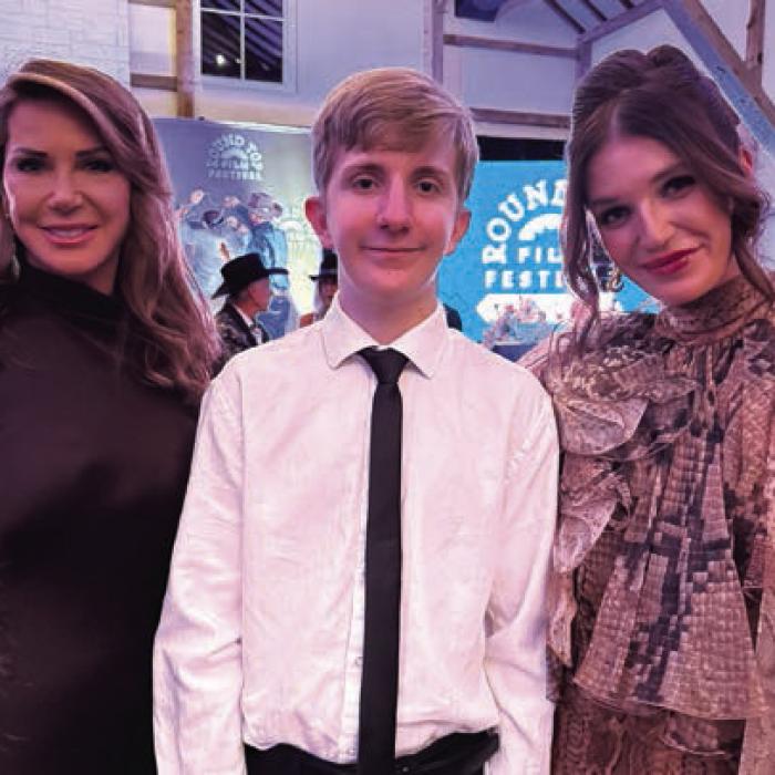 La Grange High School student Jackson Elliott, center, who participated in a screen writing workshop earlier this year put on by the Round Top Film Festival, spoke at a fundraising gala for the event in September. On either side of Elliott are the festival’s founders Shanna Schanen, left, and Skylar Schanen, right. Photo courtesy of Scott Elliott