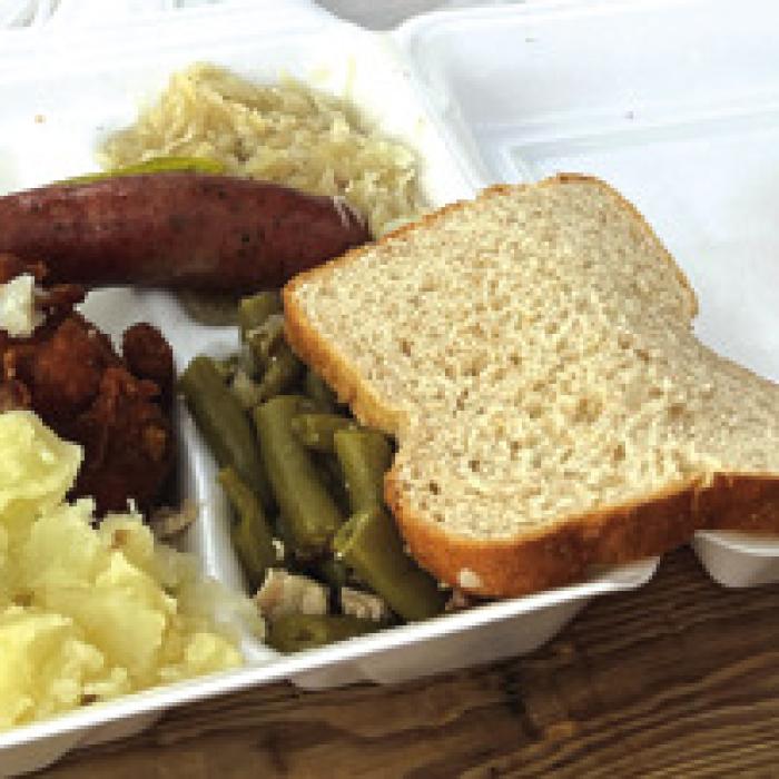 An overflowing plate of the noon meal, fried chicken, sausage and all the trimmings.