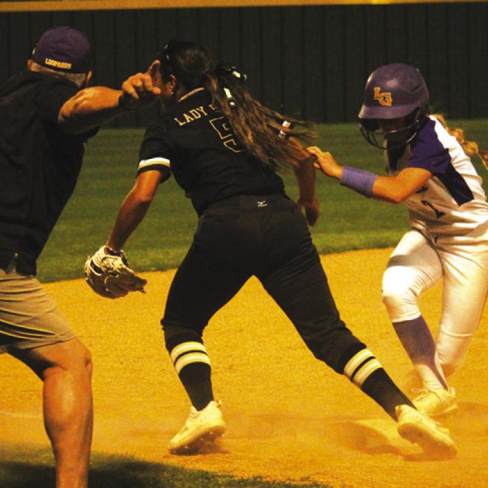 In a chaotic moment in the seventh inning of Tuesday’s game, La Grange’s Abby Cernosek, right, runs to third and gets ready to go home with the tying run (at the urging of Lady Leps head coach Ted Ferretti, left) as a Giddings throw goes into the outfi eld. Photo by Jeff Wick