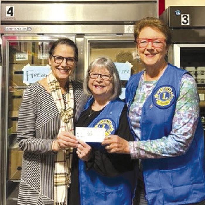 Fayetteville Lions Club president Linda Hudson donating funds to the AMEN Food Pantry.