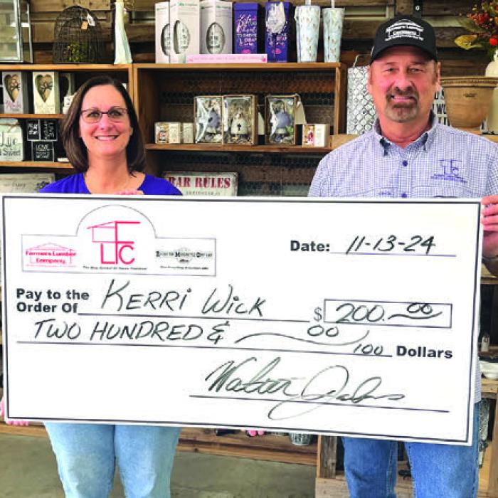 Kerri Wick, left, of La Grange, was the winner of $200 in last week’s football pick-it contest sponsored by Farmers Lumber Company. She is shown above accepting her check from Walt Jackson of Farmers. Her ballot was one of 34 perfect picks last week, but she prevailed on the score prediction tiebreaker.