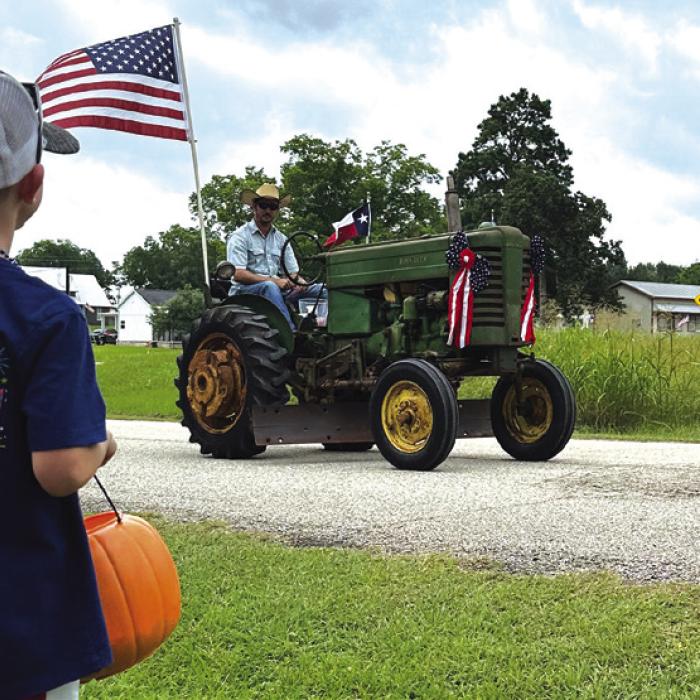 Brad Blezinger drives his grandfather’s tractor in a parade in New Ulm as his son Henry watches.