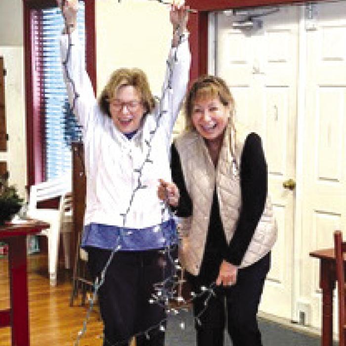 Carol Goforth and Sylvia Meinen inside the Round Top courthouse untangling Christmas lights while preparing to decorate the Round Top courthouse for Christmas.