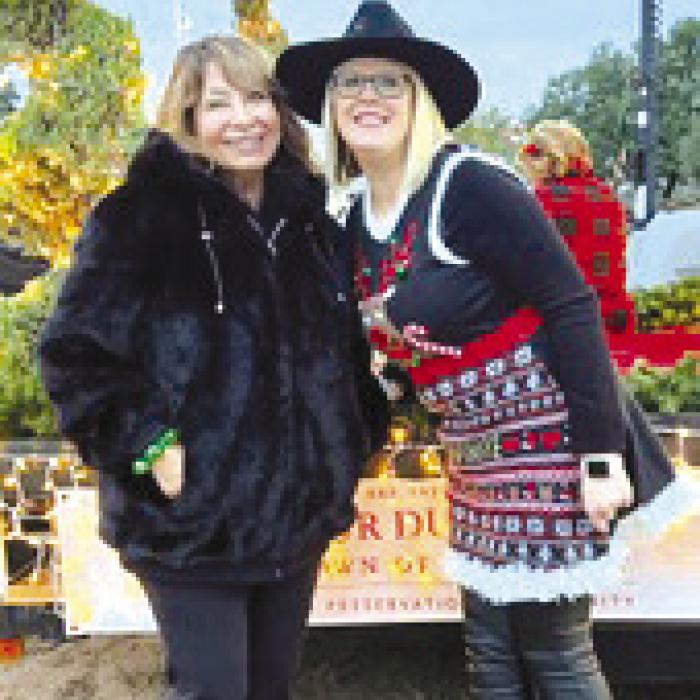 Sylvia Meinen and Ashley Marburger standing in front of the Do Your Duty Club float before the Lighted Christmas Parade.