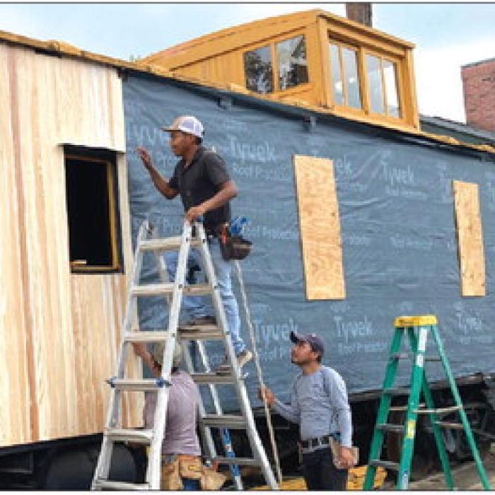 Worn and damaged boards on the side of the depot’s Katy caboose are being replaced with cypress. A new paint job will then complete the historic railcar’s refurbishing. Photo by Larry Jackson