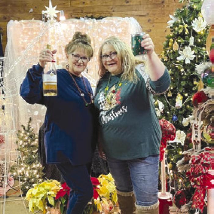 Debra Coufal Glaze and Janice Wasut serving up wine at the Christmas Tree Display.
