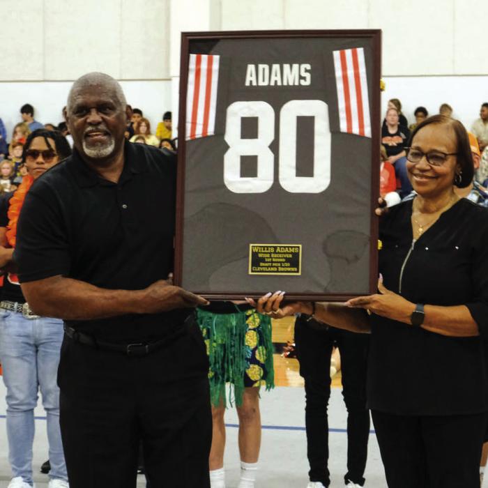 Willis Adams and his wife Natalie hold up a framed jersey that will be on display in the foyer of the Schulenburg High School Gym. The school honored the former Shorthorn during the pep rally on Friday.
