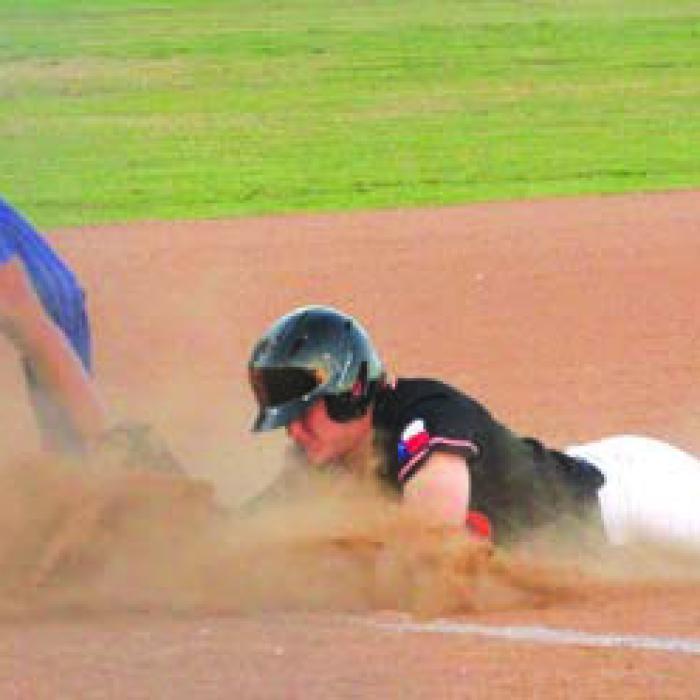 In a cloud of dust, Schulenburg’s Reid Janda slides safely into third base in Tuesday’s victory. Photo by Jeff Wick