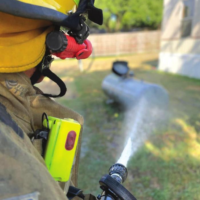 A Flatonia firefighter cools down a propane tank whose relief valve popped open by the heat Monday.