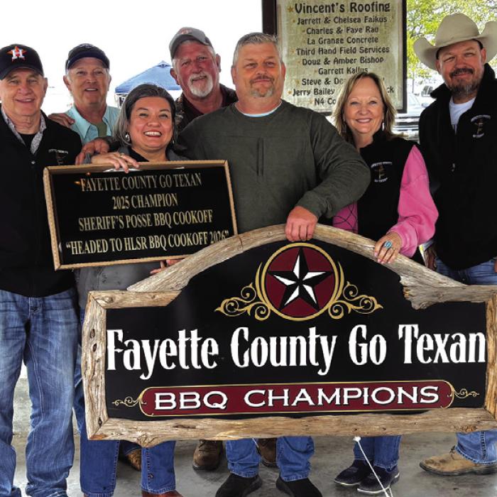 Nicole and Jason Vasut, front, accepting their championship plaque at the Fayette County Go Texan BBQ Cookoff last year.