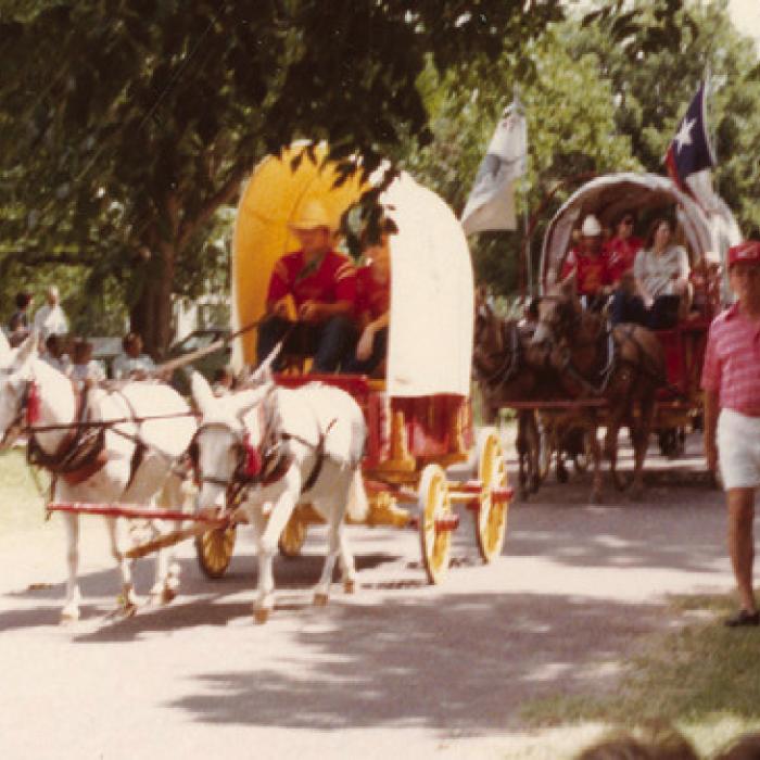 Photograph of horseback riders and covered wagons in the Fourth of July parade at Round Top in 1983.