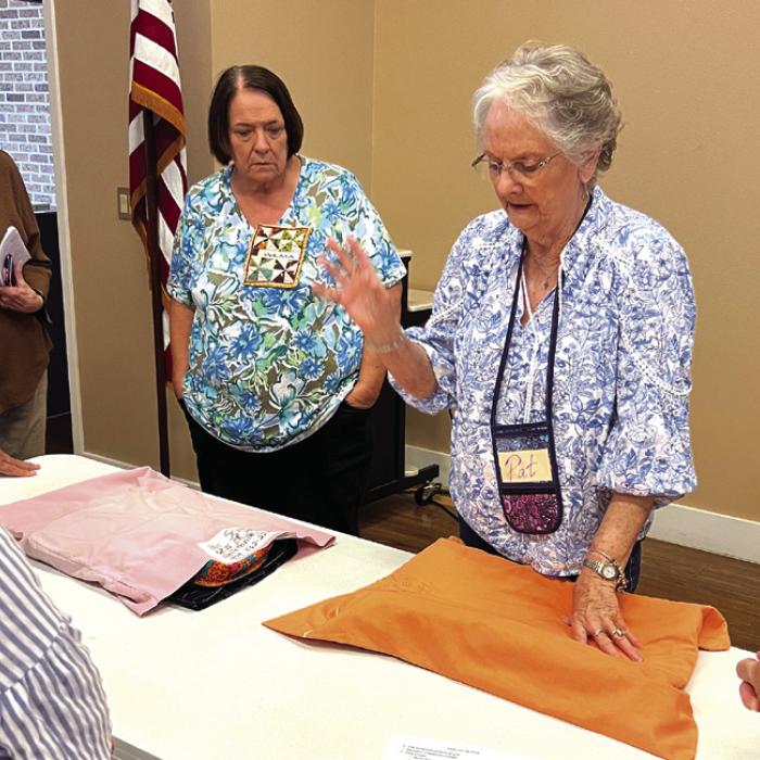 Pat Scherer demonstrating label placement with Wilma Williams and Jackie Asbill watching.