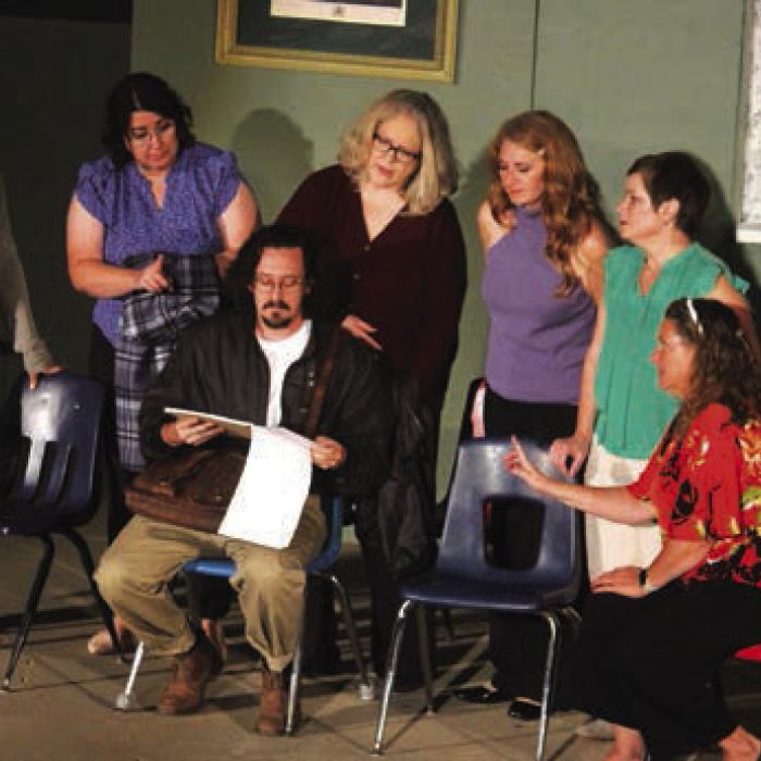 Garrett Rivas, seated center, who plays the photographer, gives his ideas for the calendar shoot to the skeptical women.