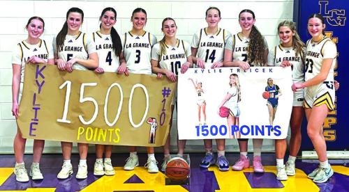 The members of the La Grange girls basketball team pose with Kylie Trlicek, center, after Tuesday’s game to honor her reaching the 1,500 career point milestone. Below, Trlicek, poses with one of her banners.