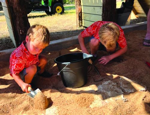 Two young visitors practice their mock excavation skills by searching for artifacts in the site’s special dig pit.