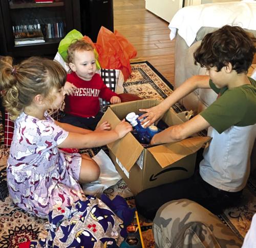 Nancie and Billie Blair’s great grandkids, Cason Blaha, Candence Schick and Luke Simpson, opening their gifts.