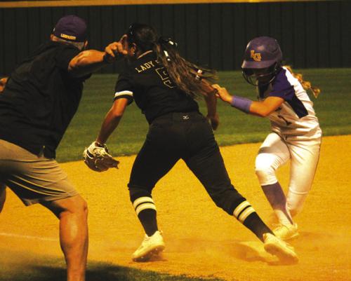 In a chaotic moment in the seventh inning of Tuesday’s game, La Grange’s Abby Cernosek, right, runs to third and gets ready to go home with the tying run (at the urging of Lady Leps head coach Ted Ferretti, left) as a Giddings throw goes into the outfi eld. Photo by Jeff Wick