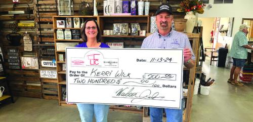 Kerri Wick, left, of La Grange, was the winner of $200 in last week’s football pick-it contest sponsored by Farmers Lumber Company. She is shown above accepting her check from Walt Jackson of Farmers. Her ballot was one of 34 perfect picks last week, but she prevailed on the score prediction tiebreaker.