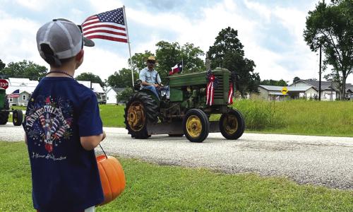 Brad Blezinger drives his grandfather’s tractor in a parade in New Ulm as his son Henry watches.