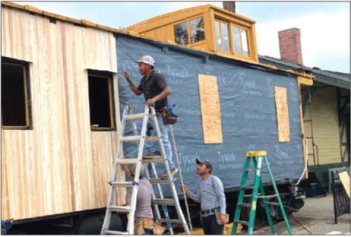 Worn and damaged boards on the side of the depot’s Katy caboose are being replaced with cypress. A new paint job will then complete the historic railcar’s refurbishing. Photo by Larry Jackson