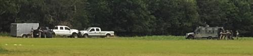 Members from the Austin County Special Response Team, right, approach the stolen vehicle and trailer, left, Wednesday off Old Plum Highway and Egypt Road.