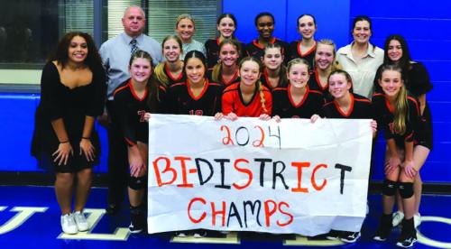 The members of the Schulenburg volleyball team pose with a banner proclaiming them Bi-District champs after their victory Monday over Kenedy in the first round of the playoffs. Photo by Audrey Kristynik