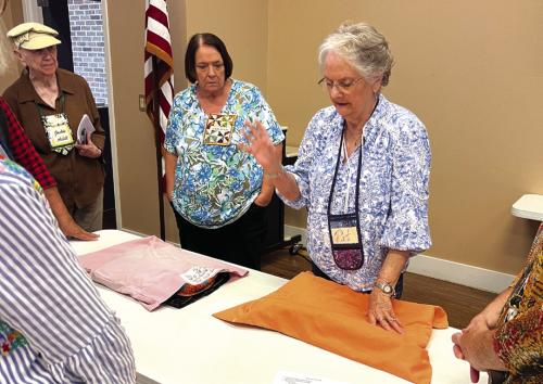 Pat Scherer demonstrating label placement with Wilma Williams and Jackie Asbill watching.