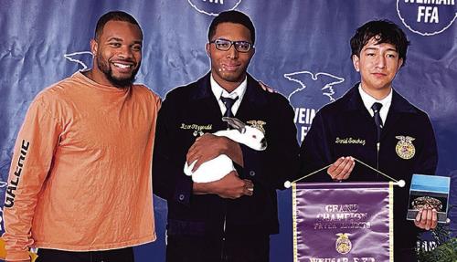 La Grange native and NFL running back J.K. Dobbins bought the grand champion rabbit for $5,000 at the Weimar Junior Livestock Shown earlier this month. Dobbins is shown here, left, with Kance Fitzgerald, center, who exhibited the grand champion fryer rabbit.