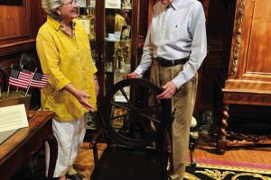 Lamar Lentz, Library and Museum Collections Curator, and Pat Johnson, Associate Curator, install the “Old Flax Spinning Wheel Chair,” an example of Colonial Revival folk art produced around the time of the 1876 Philadelphia Centennial, in the Round Top Festival Institute collection.