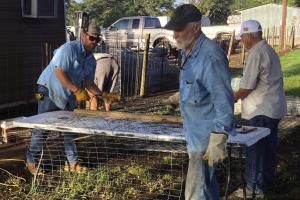 Scott Willey and Glenn Altwein cut lengths of fencing for Liberty Trees as Daniel Lewis unrolls another section of wire.