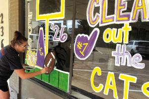 Carrie Harbers was out painting the Clear Title Company window on the courthouse square Tuesday afternoon for homecoming, which is Oct. 9. Photo by Jeff Wick