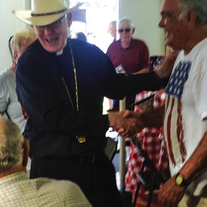 The Most Rev. Brendan J. Cahill, Bishop of the Diocese of Victoria, is pictured greeting the faithful inside the dining hall at the St. John Picnic.