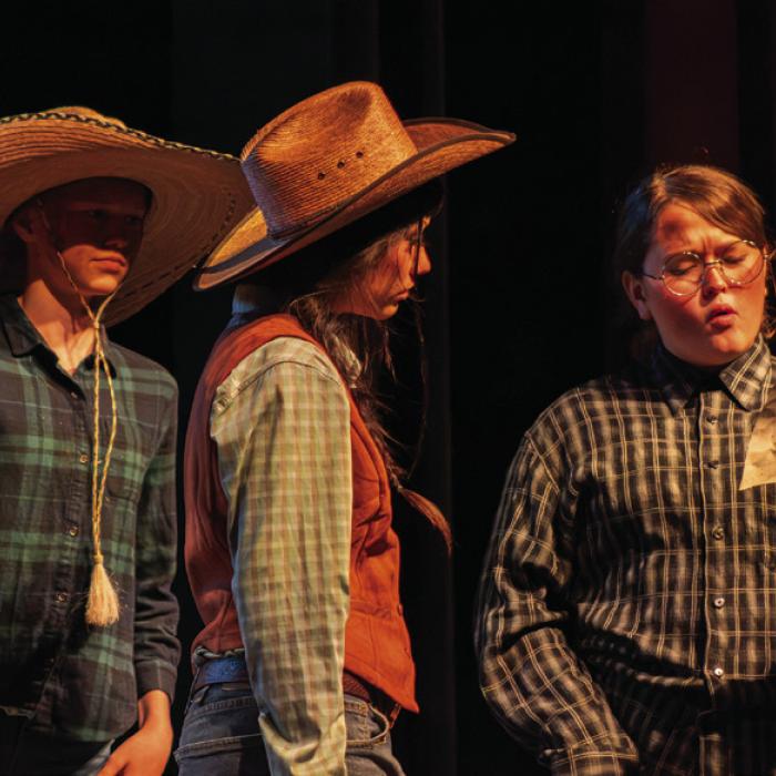 Sophia Herrera, right, reads to Bianca Carillo, center, and Reagan Zapalac, left, during a key scene during Friday’s play.