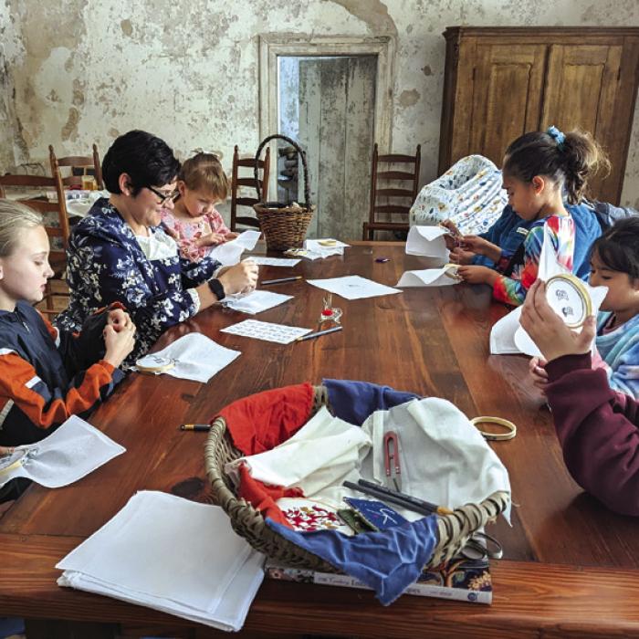 Guests gather around the table in the Kreische House to hone their sewing skills.