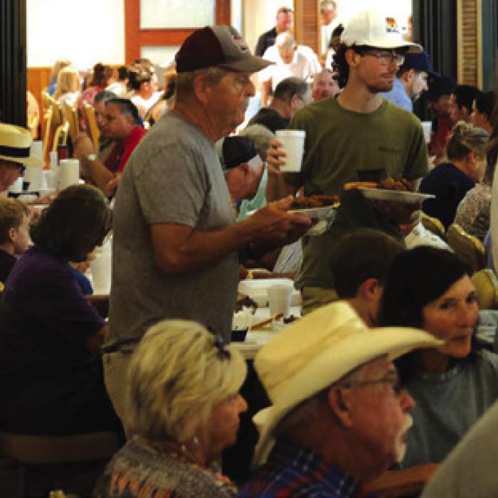 Folks look for a place to sit to eat their meal in the packed Praha parish hall.