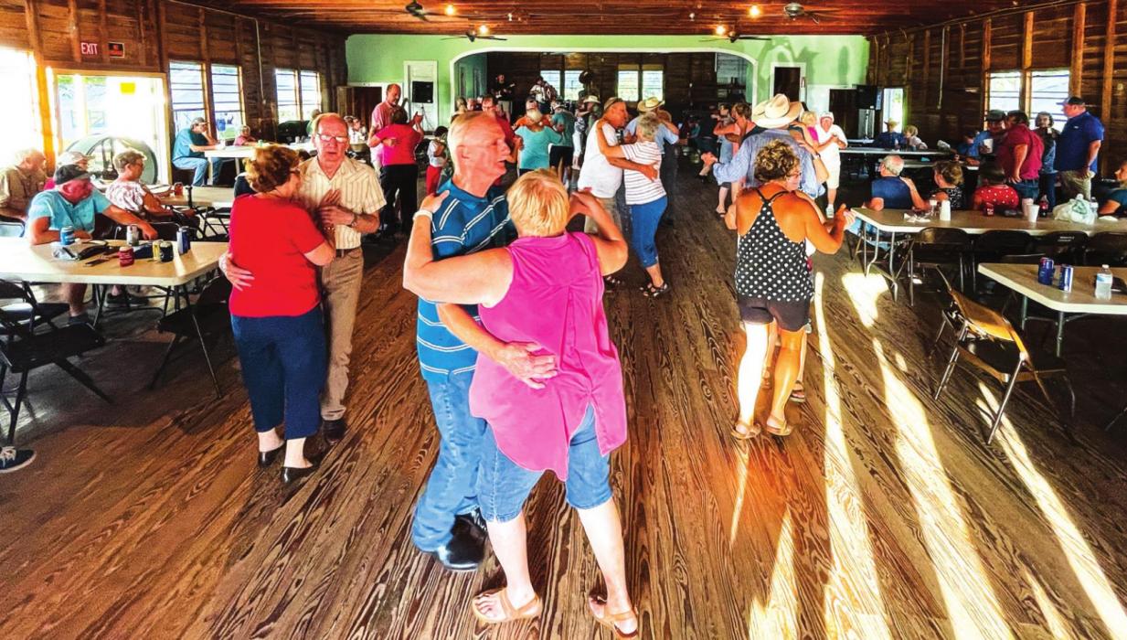 Above, a group of dancers puts a little more wear into the dancefloor at the parish hall in Moravia last Sunday, July 18. Below, a large crowd watches the live auction at the Moravia Church Picnic. Photos by Andy Behlen