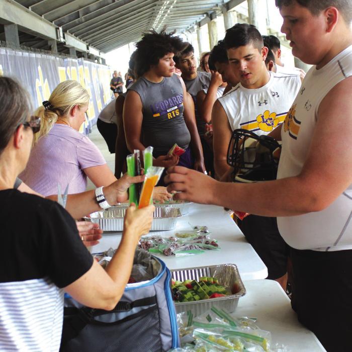 Parents handed out popsicles, watermelon and grapes to the players under the stands during a break Monday afternoon at the first day of high school football practice. Photo by Jeff Wick