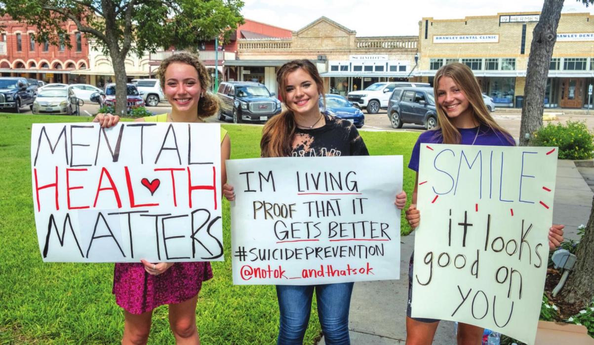 Emmi Stevens, Danyelle McIntyre, Ellee Sodolak and (not pictured) Emma Ehler held up signs along Travis Street Friday afternoon raising awareness about mental health and suicide prevention. Photo by Andy Behlen