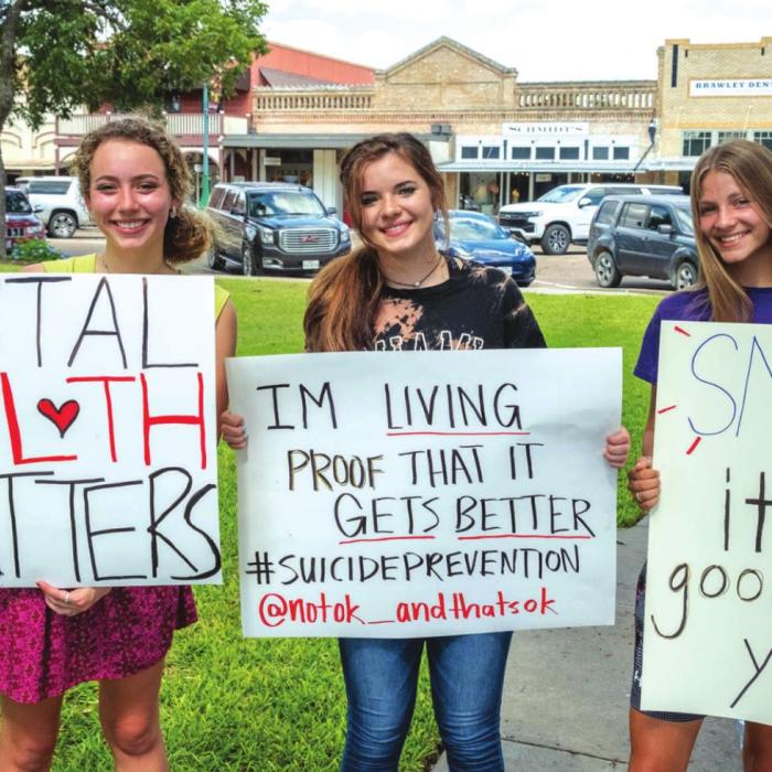Emmi Stevens, Danyelle McIntyre, Ellee Sodolak and (not pictured) Emma Ehler held up signs along Travis Street Friday afternoon raising awareness about mental health and suicide prevention. Photo by Andy Behlen