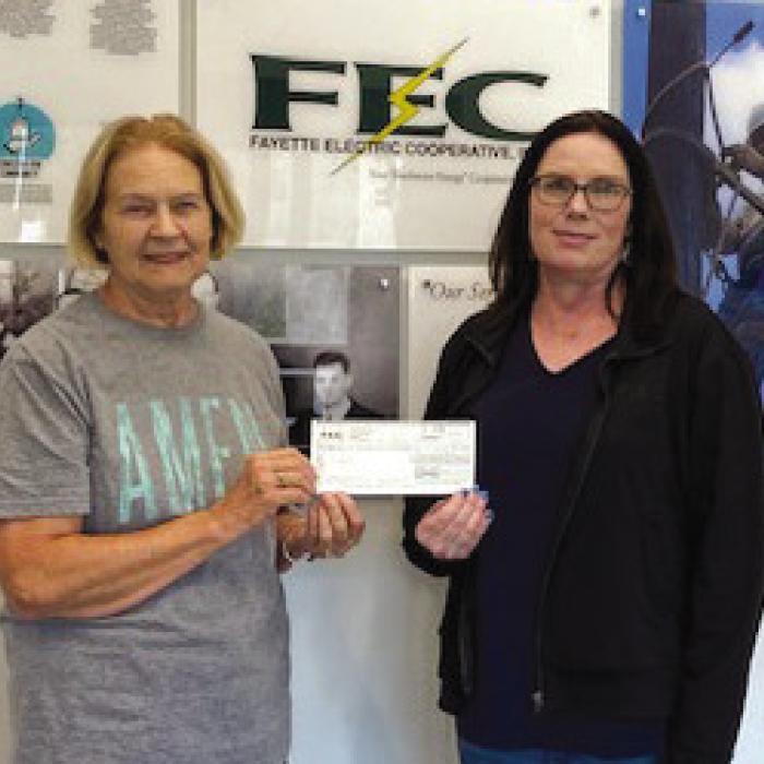 Tracy Denton, Director of Marketing at FEC, presents to Linda Oltmann, AMEN Board Member a donation of $250 for purchase of reusable bags.