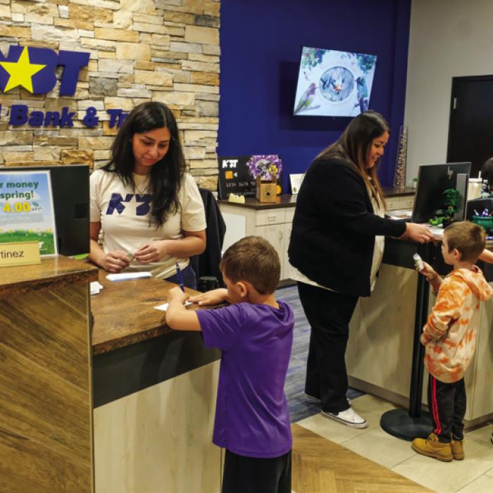 Student practiced signing their name on deposit slips with the tellers at the front of the bank. Photos by Andy Behlen