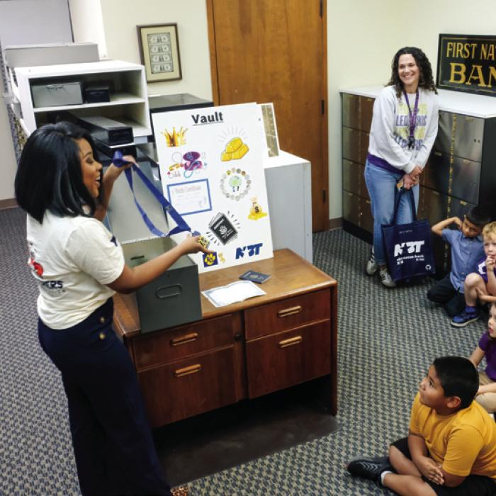 NBT’s Traye Wright shows the students items someone might want to store in a safe deposit box, such as the medal she is holding.